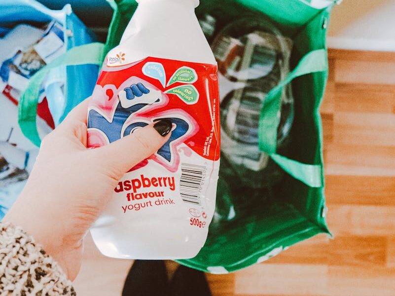 Person Holding Red and White Disposable Bottle