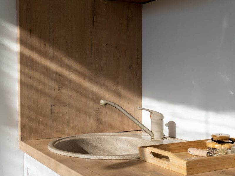 A modern minimalist kitchen showcasing a wooden sink area with natural sunlight.