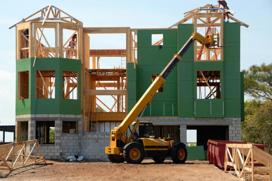 yellow and black heavy equipment near unfinished building