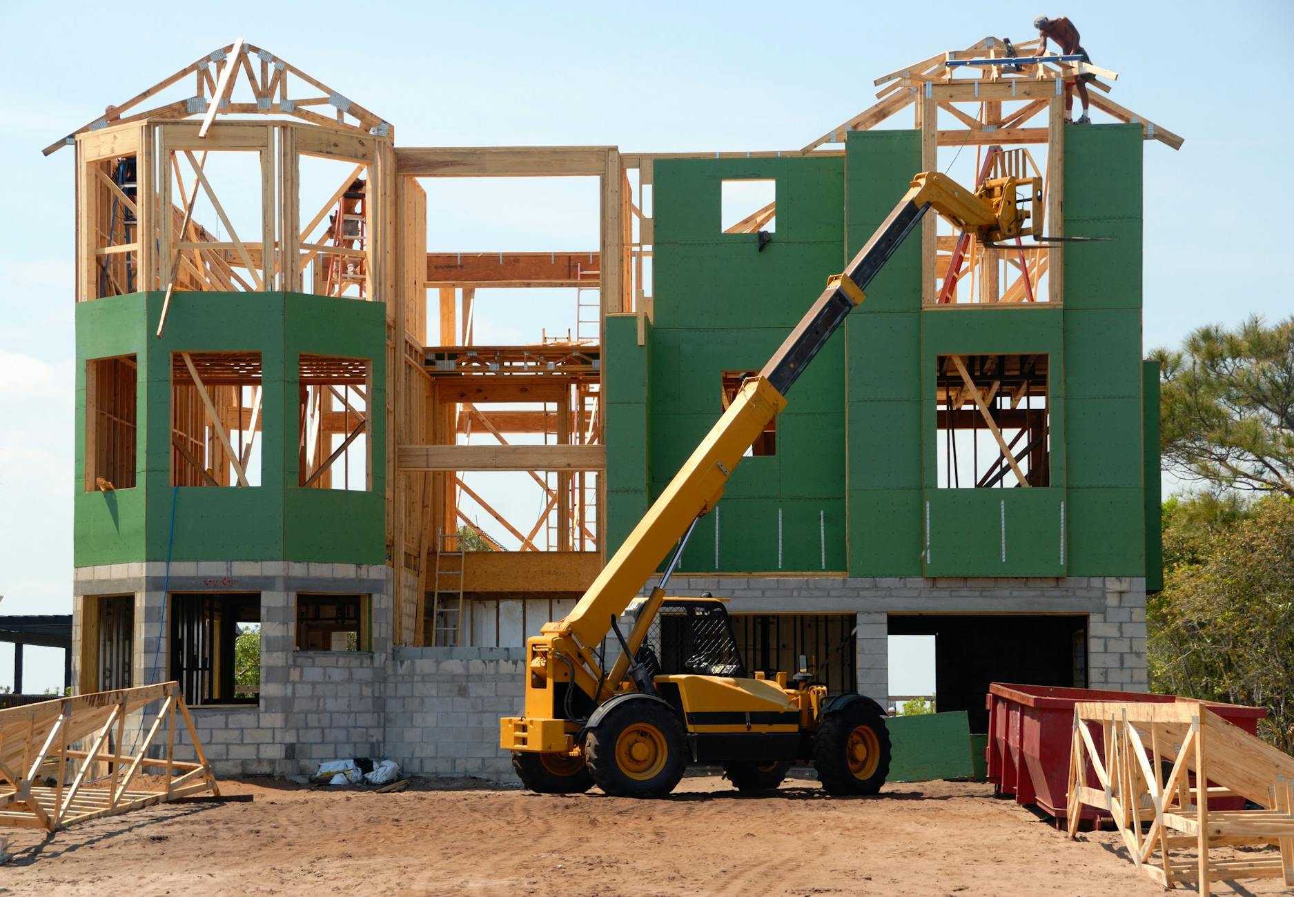 yellow and black heavy equipment near unfinished building