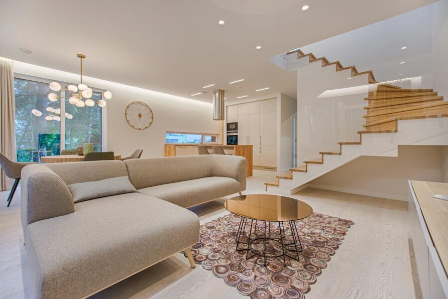 Contemporary living room with neutral tones, a sleek sofa, and elegant wooden staircase.