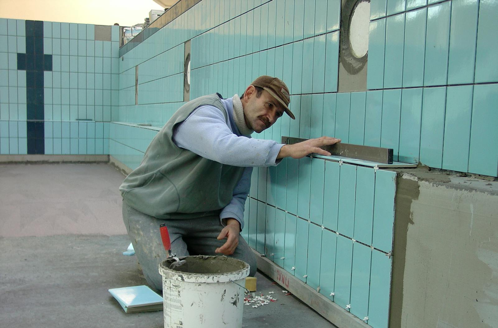 Tiler expertly aligns ceramic tiles on a swimming pool wall. Indoor construction setting in Wrocław.