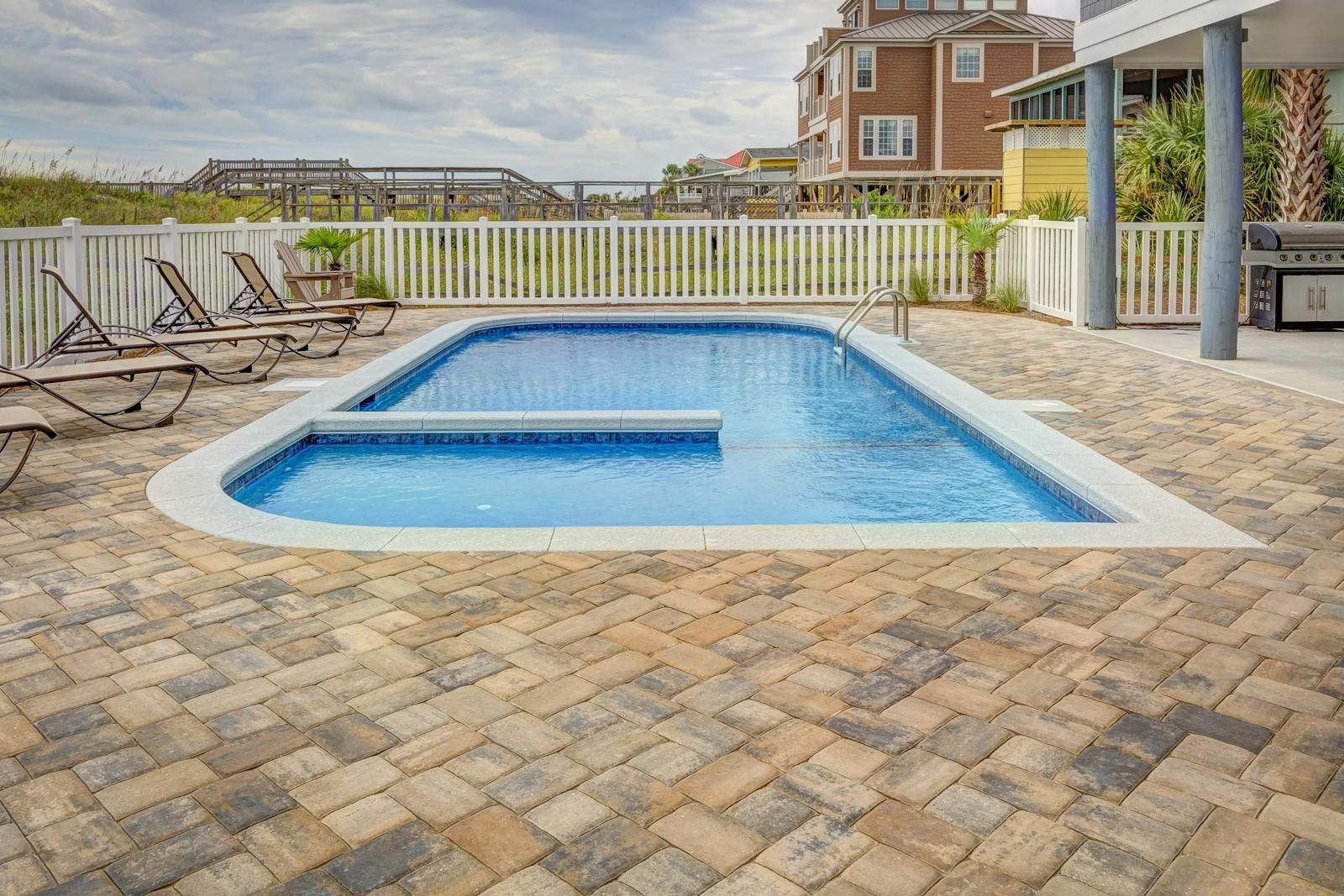 Relaxing poolside patio with sun loungers and villas, perfect for a summer retreat.